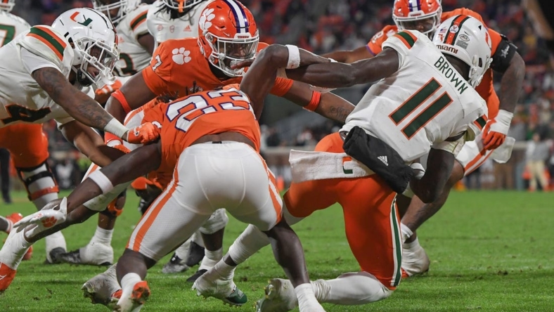 Nov 19, 2022; Clemson, South Carolina, USA; Clemson Tigers defensive end Justin Mascoll (7) pushes over Miami Hurricanes quarterback Jacurri Brown (11) for a safety during the third quarter at Memorial Stadium. Mandatory Credit: Ken Ruinard-USA TODAY Sports