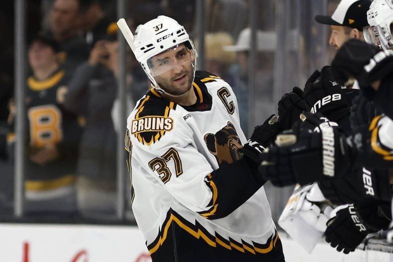 Nov 19, 2022; Boston, Massachusetts, USA; Boston Bruins center Patrice Bergeron (37) is congratulated at the bench after scoring against the Chicago Blackhawks during the second period at TD Garden. Mandatory Credit: Winslow Townson-USA TODAY Sports