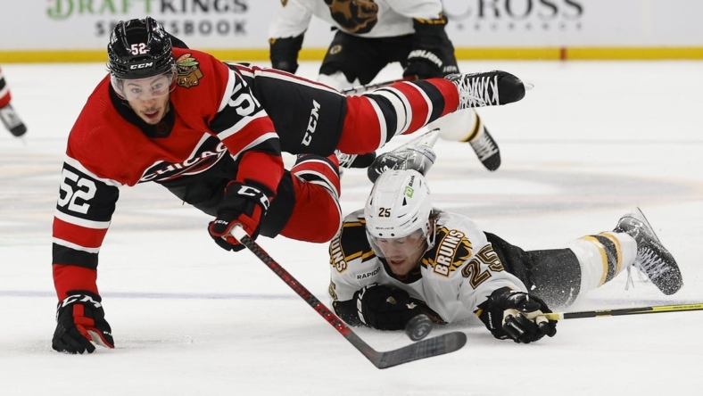 Nov 19, 2022; Boston, Massachusetts, USA; Chicago Blackhawks center Reese Johnson (52) is upended by Boston Bruins defenseman Brandon Carlo (25) during the second period at TD Garden. Mandatory Credit: Winslow Townson-USA TODAY Sports
