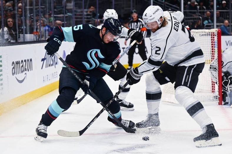 Nov 19, 2022; Seattle, Washington, USA; Seattle Kraken left wing Andre Burakovsky (95) and Los Angeles Kings defenseman Alexander Edler (2) fight for the puck during the first period at Climate Pledge Arena. Mandatory Credit: Steven Bisig-USA TODAY Sports