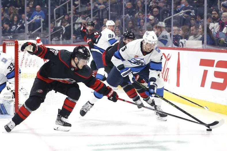 Nov 21, 2022; Winnipeg, Manitoba, CAN; Carolina Hurricanes right wing Jesper Fast (71) and Winnipeg Jets defenseman Brenden Dillon (5) chase for the puck in the first period at Canada Life Centre. Mandatory Credit: James Carey Lauder-USA TODAY Sports