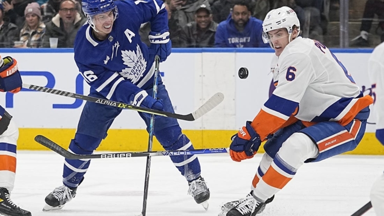 Nov 21, 2022; Toronto, Ontario, CAN; New York Islanders defenseman Ryan Pulock (6) and Toronto Maple Leafs forward Mitchell Marner (16) play for the puck during the first period at Scotiabank Arena. Mandatory Credit: John E. Sokolowski-USA TODAY Sports