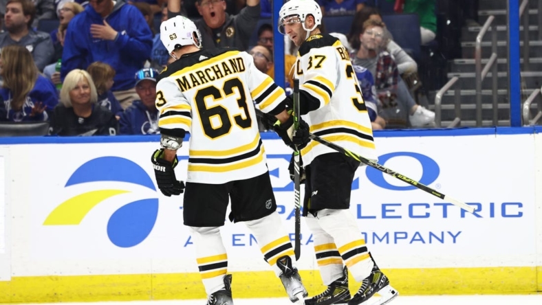 Nov 21, 2022; Tampa, Florida, USA; Boston Bruins celebrate center Patrice Bergeron (37) 1000th career point after getting the assist on the goal scored by left wing Brad Marchand (63) during the second period against the Tampa Bay Lightning at Amalie Arena. Mandatory Credit: Kim Klement-USA TODAY Sports