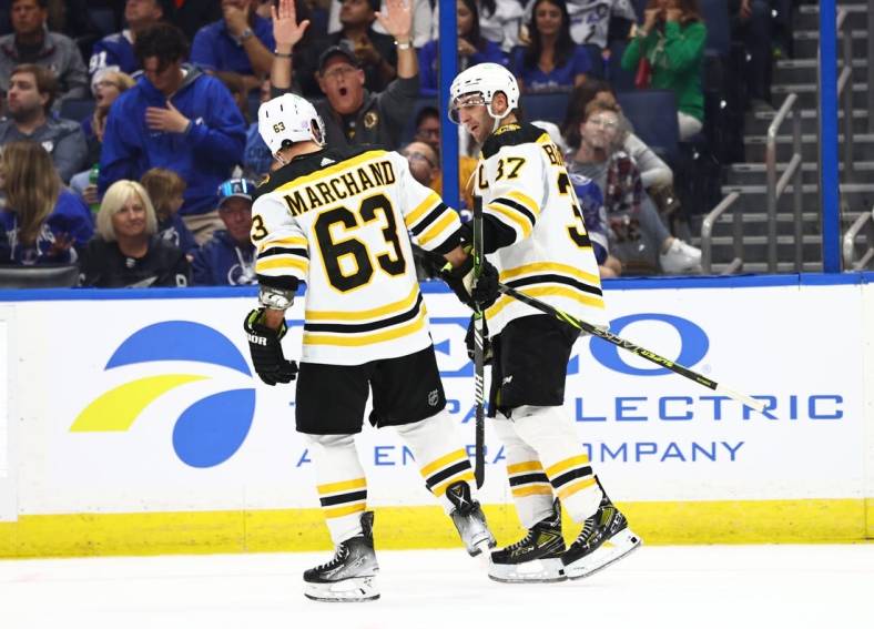 Nov 21, 2022; Tampa, Florida, USA; Boston Bruins celebrate center Patrice Bergeron (37) 1000th career point after getting the assist on the goal scored by left wing Brad Marchand (63) during the second period against the Tampa Bay Lightning at Amalie Arena. Mandatory Credit: Kim Klement-USA TODAY Sports