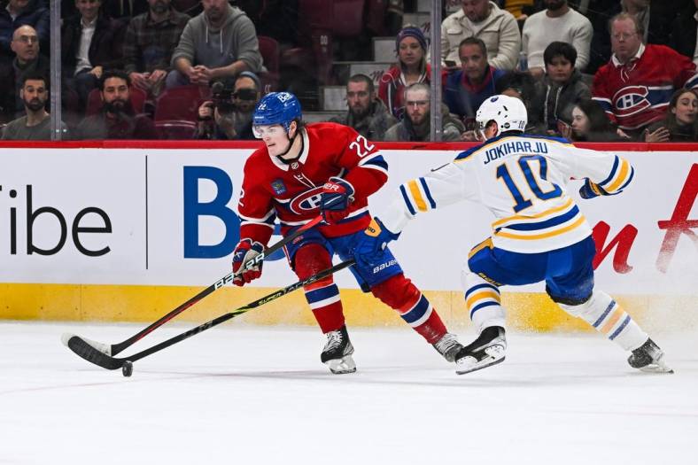 Nov 22, 2022; Montreal, Quebec, CAN; Montreal Canadiens right wing Cole Caufield (22) plays the puck against Buffalo Sabres defenseman Henri Jokiharju (10) during the first period at Bell Centre. Mandatory Credit: David Kirouac-USA TODAY Sports