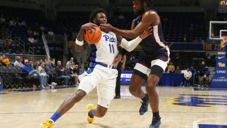 Nov 22, 2022; Pittsburgh, Pennsylvania, USA;  Pittsburgh Panthers guard Jamarius Burton (11) dribbles the ball against Fairleigh Dickinson Knights forward Ansley Almonor (right) during the first half at the Petersen Events Center. Mandatory Credit: Charles LeClaire-USA TODAY Sports