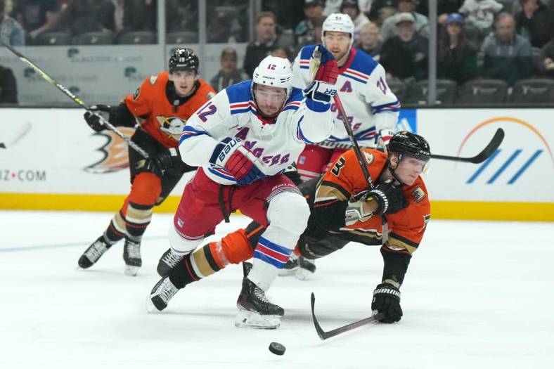 Nov 23, 2022; Anaheim, California, USA; New York Rangers right wing Julien Gauthier (12) and Anaheim Ducks defenseman John Klingberg (3) battle for the puck in the first period at Honda Center. Mandatory Credit: Kirby Lee-USA TODAY Sports