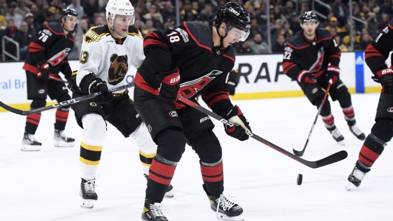 Nov 25, 2022; Boston, Massachusetts, USA; Carolina Hurricanes center Jack Drury (18) tries to gain control of the puck in front of Boston Bruins center Charlie Coyle (13) during the first period at TD Garden. Mandatory Credit: Bob DeChiara-USA TODAY Sports