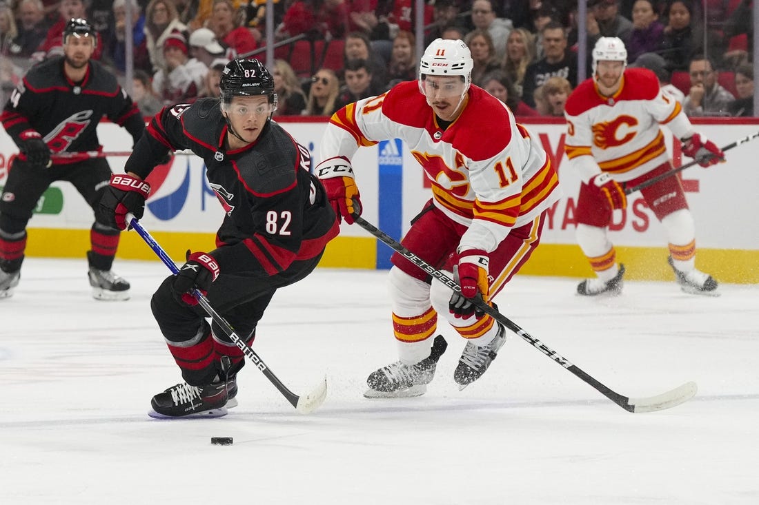 Nov 26, 2022; Raleigh, North Carolina, USA; Carolina Hurricanes center Jesperi Kotkaniemi (82) carries the puck past Calgary Flames center Mikael Backlund (11) during the first period at PNC Arena. Mandatory Credit: James Guillory-USA TODAY Sports