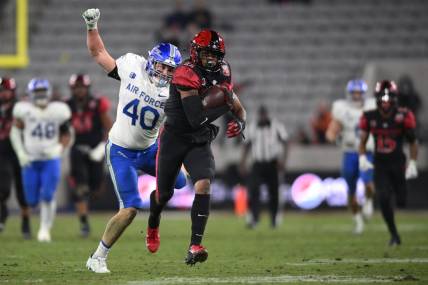 Nov 26, 2022; San Diego, California, USA; San Diego State Aztecs wide receiver Brionne Penny (11) runs with the ball as Air Force Falcons linebacker Alec Mock (40) prepares to punch the ball during the second half at Snapdragon Stadium. Mandatory Credit: Orlando Ramirez-USA TODAY Sports