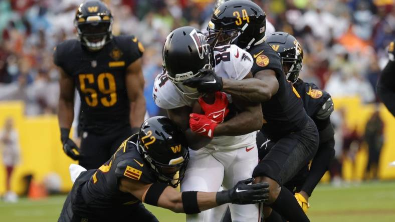 Nov 27, 2022; Landover, Maryland, USA; Atlanta Falcons running back Cordarrelle Patterson (84) has his face mask grabbed by Washington Commanders cornerback Christian Holmes (34) while running with the ball during the first quarter at FedExField. Mandatory Credit: Geoff Burke-USA TODAY Sports