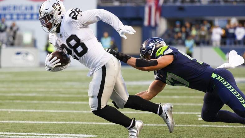 Nov 27, 2022; Seattle, Washington, USA; Las Vegas Raiders running back Josh Jacobs (28) breaks a tackle attempt by Seattle Seahawks linebacker Cody Barton (57) after making a reception during the fourth quarter at Lumen Field. Mandatory Credit: Joe Nicholson-USA TODAY Sports