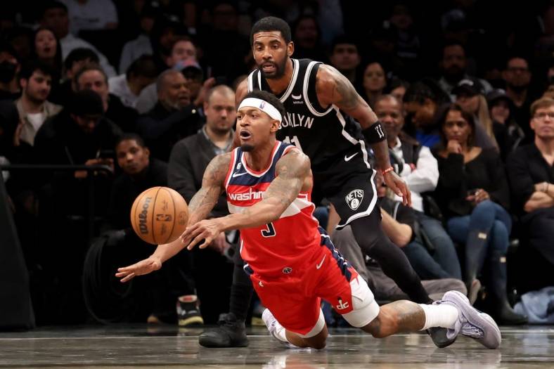 Nov 30, 2022; Brooklyn, New York, USA; Washington Wizards guard Bradley Beal (3) passes the ball as he falls away from Brooklyn Nets guard Kyrie Irving (11) during the second quarter at Barclays Center. Mandatory Credit: Brad Penner-USA TODAY Sports