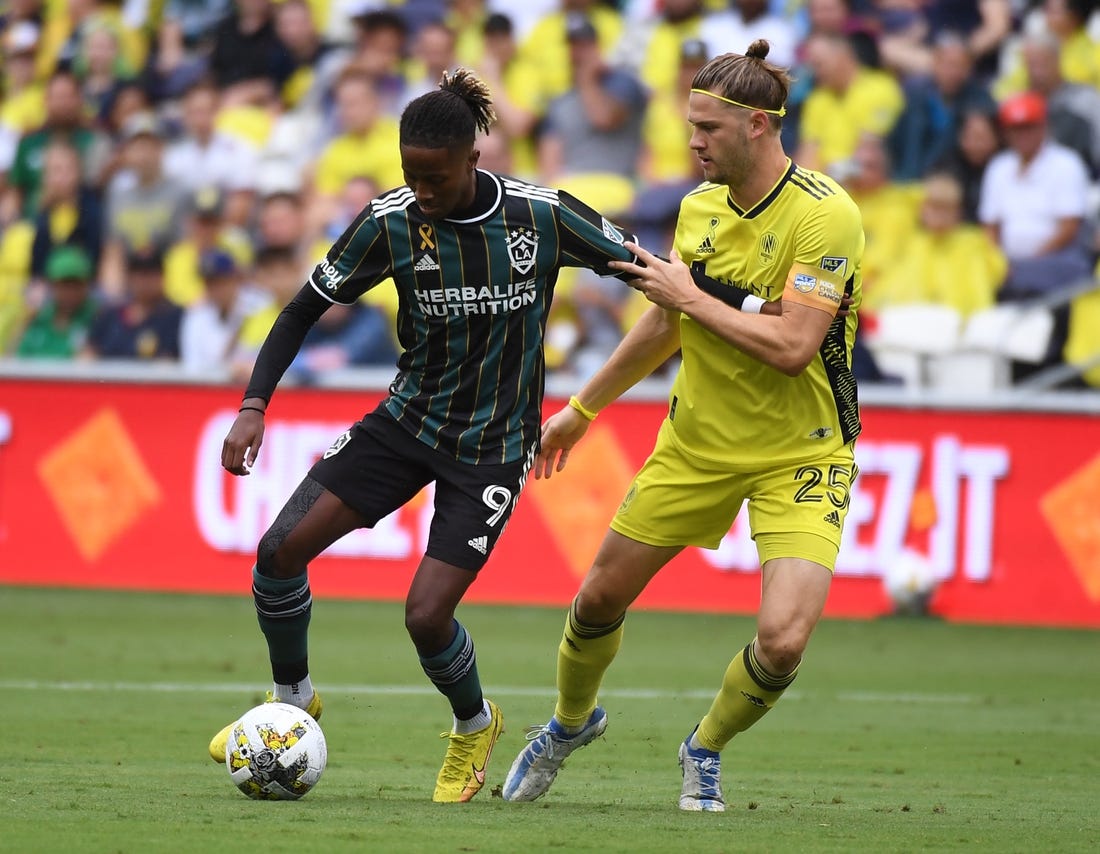 Sep 10, 2022; Nashville, Tennessee, USA; Los Angeles Galaxy forward Kevin Cabral (9) works against Nashville SC defender Walker Zimmerman (25) during the first half at Geodis Park. Mandatory Credit: Christopher Hanewinckel-USA TODAY Sports