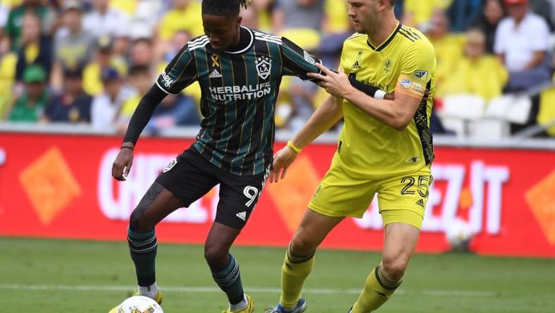 Sep 10, 2022; Nashville, Tennessee, USA; Los Angeles Galaxy forward Kevin Cabral (9) works against Nashville SC defender Walker Zimmerman (25) during the first half at Geodis Park. Mandatory Credit: Christopher Hanewinckel-USA TODAY Sports