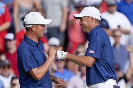 Sep 24, 2022; Charlotte, North Carolina, USA; Team USA golfer Justin Thomas (left) and golfer Jordan Spieth (right) celebrate after winning the match on the 15th green during the four-ball match play of the Presidents Cup golf tournament at Quail Hollow Club. Mandatory Credit: Jim Dedmon-USA TODAY Sports