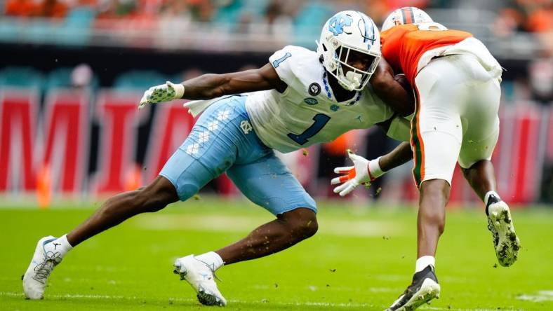 Oct 8, 2022; Miami Gardens, Florida, USA; North Carolina Tar Heels defensive back Tony Grimes (1) tackles Miami Hurricanes wide receiver Frank Ladson Jr. (8) during the first half at Hard Rock Stadium. Mandatory Credit: Rich Storry-USA TODAY Sports