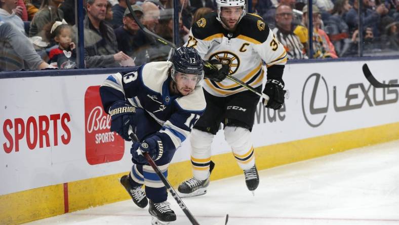 Oct 28, 2022; Columbus, Ohio, USA; Columbus Blue Jackets left wing Johnny Gaudreau (13) and Boston Bruins center Patrice Bergeron (37) play for the puck during the second period at Nationwide Arena. Mandatory Credit: Russell LaBounty-USA TODAY Sports
