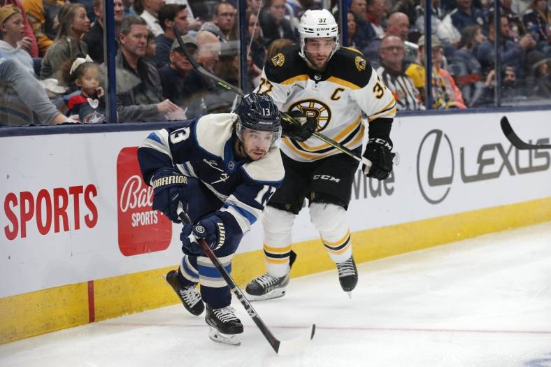 Oct 28, 2022; Columbus, Ohio, USA; Columbus Blue Jackets left wing Johnny Gaudreau (13) and Boston Bruins center Patrice Bergeron (37) play for the puck during the second period at Nationwide Arena. Mandatory Credit: Russell LaBounty-USA TODAY Sports