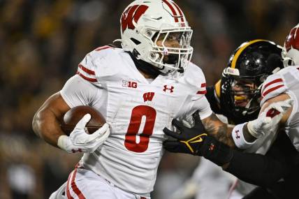 Nov 12, 2022; Iowa City, Iowa, USA; Wisconsin Badgers running back Braelon Allen (0) runs the ball as Iowa Hawkeyes defensive lineman Lukas Van Ness (91) looks to make the tackle during the fourth quarter at Kinnick Stadium. Mandatory Credit: Jeffrey Becker-USA TODAY Sports