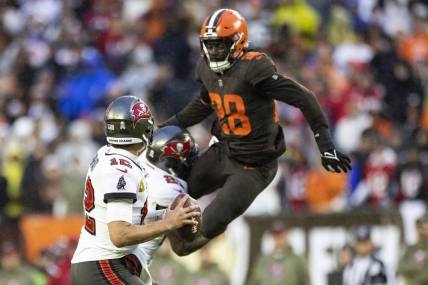 Nov 27, 2022; Cleveland, Ohio, USA; Tampa Bay Buccaneers quarterback Tom Brady (12) looks for a receiver as Cleveland Browns linebacker Jeremiah Owusu-Koramoah (28) leaps to block the pass during overtime at FirstEnergy Stadium. Mandatory Credit: Scott Galvin-USA TODAY Sports