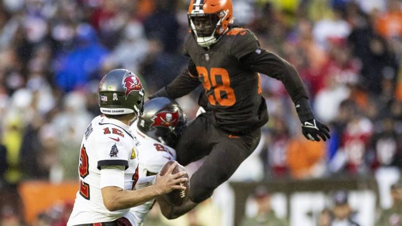 Nov 27, 2022; Cleveland, Ohio, USA; Tampa Bay Buccaneers quarterback Tom Brady (12) looks for a receiver as Cleveland Browns linebacker Jeremiah Owusu-Koramoah (28) leaps to block the pass during overtime at FirstEnergy Stadium. Mandatory Credit: Scott Galvin-USA TODAY Sports