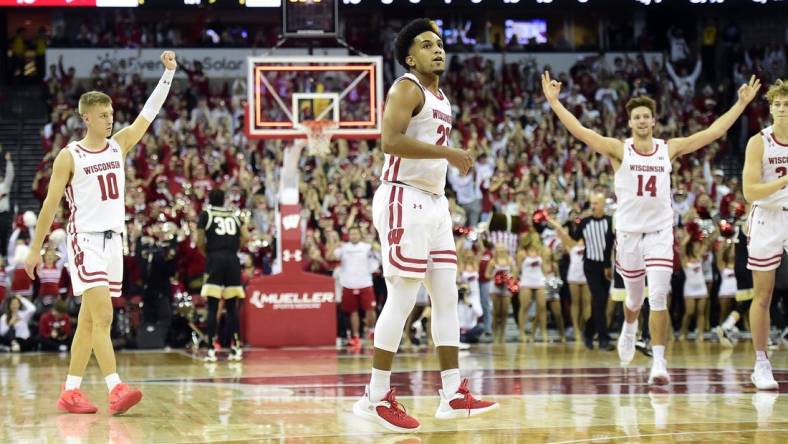 Nov 29, 2022; Madison, Wisconsin, USA;  Wisconsin Badgers guard Chucky Hepburn (23) looks on as teammates Isaac Lindsey (10) and Carter Gilmore (14) celebrate his buzzer-beating shot at the end of the first half at the Kohl Center. Mandatory Credit: Kayla Wolf-USA TODAY Sports