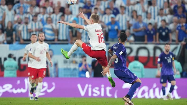 Nov 30, 2022; Doha, Qatar; Poland forward Karol Swiderski (16) leaps for a header past Argentina defender Cristian Romero (13) during the second half in a group stage match during the 2022 World Cup at Stadium 974. Mandatory Credit: Danielle Parhizkaran-USA TODAY Sports