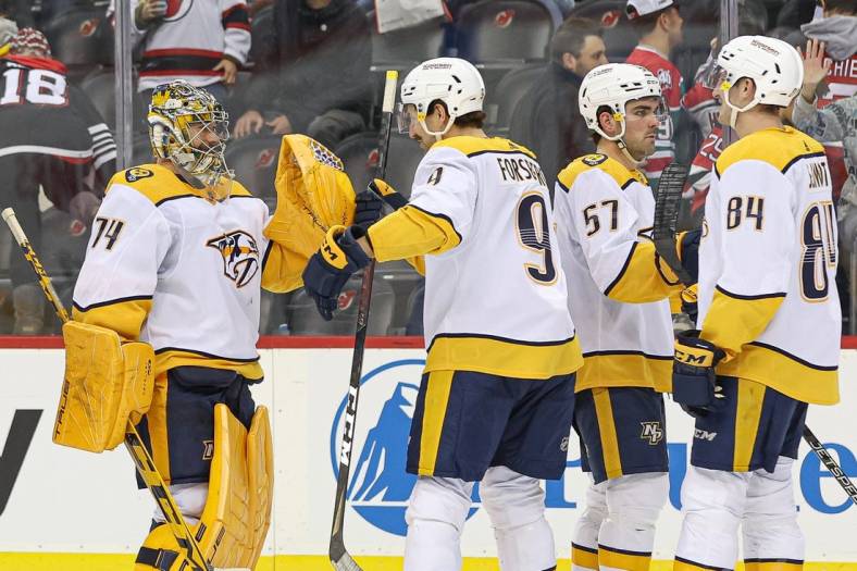 Dec 1, 2022; Newark, New Jersey, USA; Nashville Predators goaltender Juuse Saros (74) celebrates with left wing Filip Forsberg (9) after defeating the New Jersey Devils in overtime at Prudential Center. Mandatory Credit: Vincent Carchietta-USA TODAY Sports