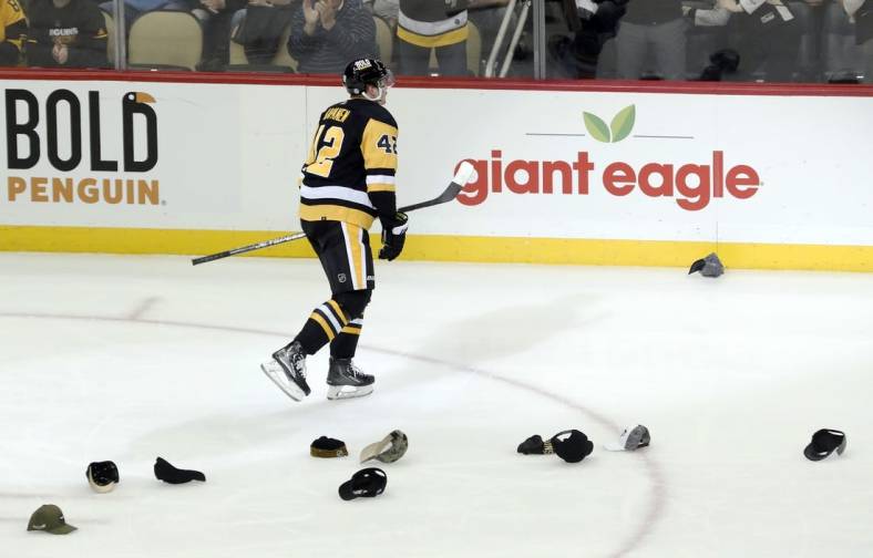 Dec 3, 2022; Pittsburgh, Pennsylvania, USA;  Pittsburgh Penguins right wing Kasperi Kapanen (42) skates past hats thrown onto the ice in celebration of his third goal of the game to record a hat trick against the St. Louis Blues during the second period at PPG Paints Arena. Mandatory Credit: Charles LeClaire-USA TODAY Sports