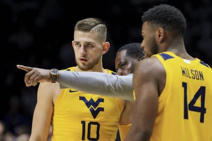 Dec 3, 2022; Cincinnati, Ohio, USA;  West Virginia Mountaineers assistant coach Larry Harrison, middle, talks with guard Erik Stevenson (10) and guard Seth Wilson (14) during a stop in play against the Xavier Musketeers in the second half at Cintas Center. Mandatory Credit: Aaron Doster-USA TODAY Sports
