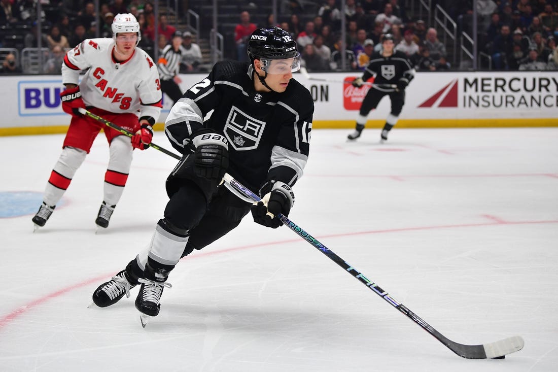 Dec 3, 2022; Los Angeles, California, USA; Los Angeles Kings left wing Trevor Moore (12) moves the puck ahead of Carolina Hurricanes right wing Andrei Svechnikov (37) during the first period at Crypto.com Arena. Mandatory Credit: Gary A. Vasquez-USA TODAY Sports