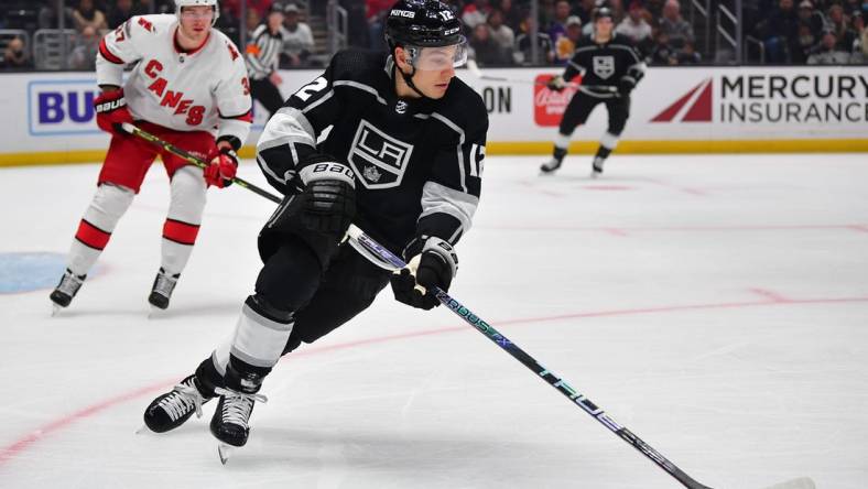 Dec 3, 2022; Los Angeles, California, USA; Los Angeles Kings left wing Trevor Moore (12) moves the puck ahead of Carolina Hurricanes right wing Andrei Svechnikov (37) during the first period at Crypto.com Arena. Mandatory Credit: Gary A. Vasquez-USA TODAY Sports