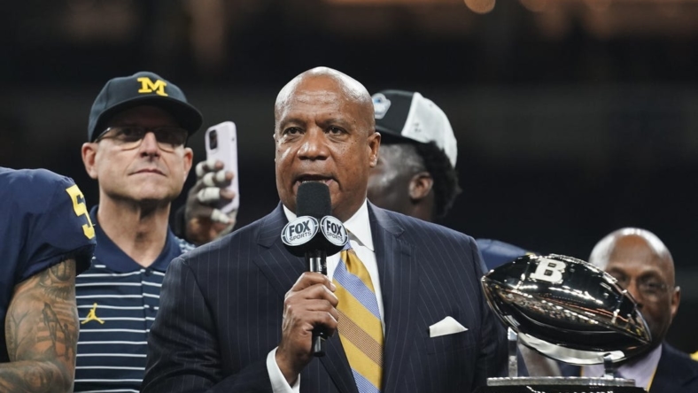 Dec 3, 2022; Indianapolis, Indiana, USA;  Big Ten Commissioner Kevin Warren presents the championship trophy to Michigan Wolverines head coach Jim Harbaugh following their 43-22 victory against Purdue in the Big Ten Championship at Lucas Oil Stadium. Mandatory Credit: Robert Goddin-USA TODAY Sports