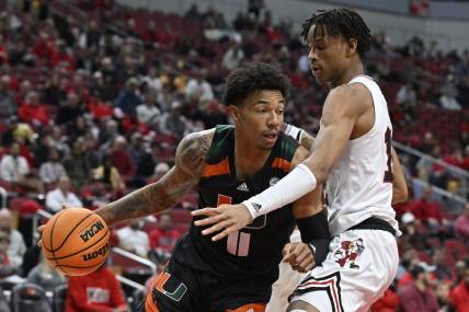 Dec 4, 2022; Louisville, Kentucky, USA;  Miami (Fl) Hurricanes guard Jordan Miller (11) dribbles against Louisville Cardinals forward JJ Traynor (12) during the first half at KFC Yum! Center. Mandatory Credit: Jamie Rhodes-USA TODAY Sports