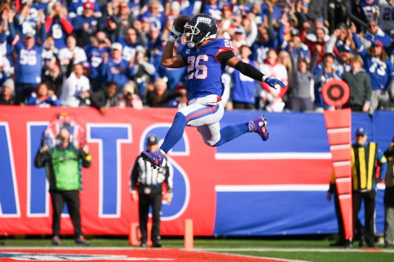 Dec 4, 2022; East Rutherford, New Jersey, USA; New York Giants running back Saquon Barkley (26) leaps into the end zone for a touchdown against the Washington Commanders during the first half at MetLife Stadium. Mandatory Credit: Rich Barnes-USA TODAY Sports
