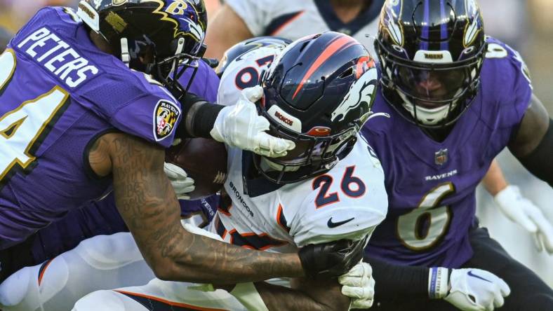 Dec 4, 2022; Baltimore, Maryland, USA; Baltimore Ravens linebacker Jason Pierre-Paul (4) and cornerback Marcus Peters (24) tackle Denver Broncos running back Mike Boone (26)  during the second half  at M&T Bank Stadium. Mandatory Credit: Tommy Gilligan-USA TODAY Sports