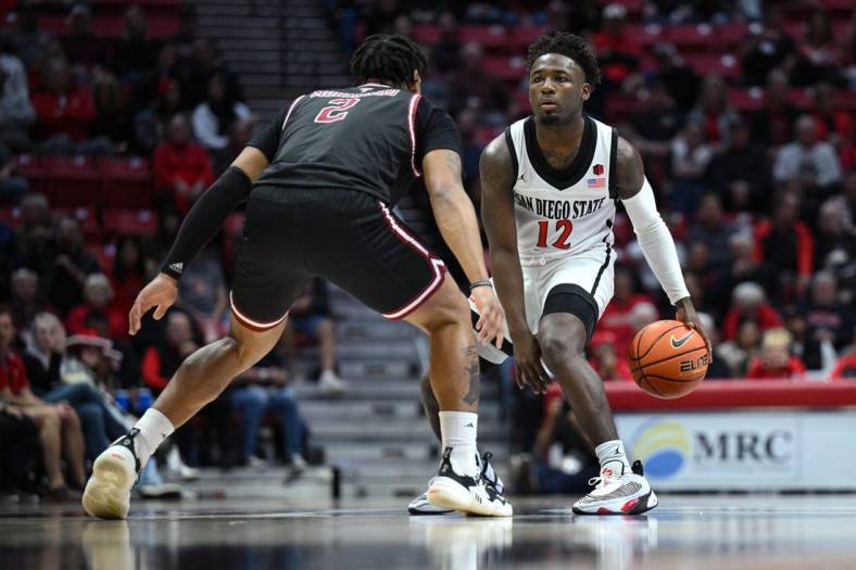 Dec 5, 2022; San Diego, California, USA; San Diego State Aztecs guard Darrion Trammell (12) dribbles the ball while defended by Troy Trojans guard Aamer Muhammad (2) during the first half at Viejas Arena. Mandatory Credit: Orlando Ramirez-USA TODAY Sports