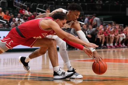 Dec 7, 2022; Coral Gables, Florida, USA; Miami Hurricanes guard Jordan Miller (11) and Cornell Big Red guard Chris Manon (30) battle for a loose ball during the first half at Watsco Center. Mandatory Credit: Jasen Vinlove-USA TODAY Sports