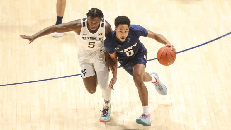 Dec 7, 2022; Morgantown, West Virginia, USA; Navy Midshipmen guard Austin Inge (0) dribbles against West Virginia Mountaineers guard Joe Toussaint (5) during the first half at WVU Coliseum. Mandatory Credit: Ben Queen-USA TODAY Sports