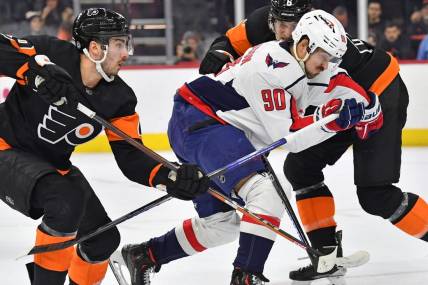 Dec 7, 2022; Philadelphia, Pennsylvania, USA; Washington Capitals left wing Marcus Johansson (90) is defended by Philadelphia Flyers left wing Noah Cates (49) and defenseman Travis Sanheim (6) during the first period at Wells Fargo Center. Mandatory Credit: Eric Hartline-USA TODAY Sports