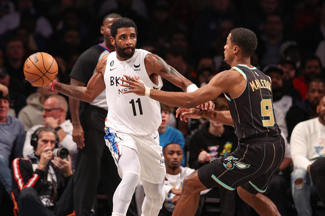 Dec 7, 2022; Brooklyn, New York, USA; Brooklyn Nets guard Kyrie Irving (11) passes the ball during the first half as Charlotte Hornets guard Theo Maledon (9) defends at Barclays Center. Mandatory Credit: Vincent Carchietta-USA TODAY Sports