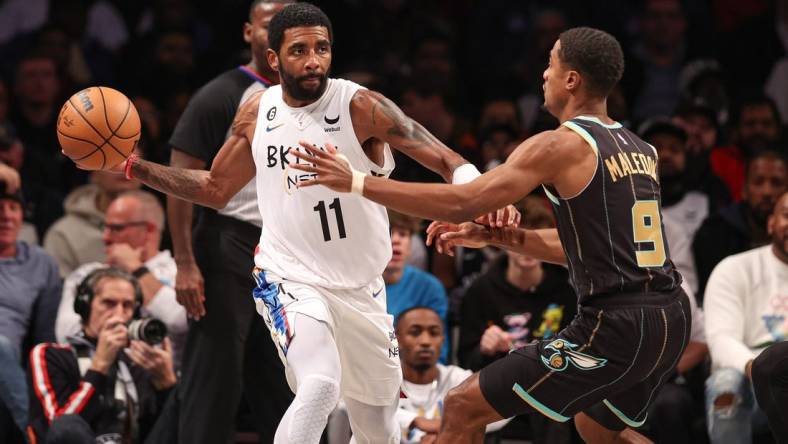 Dec 7, 2022; Brooklyn, New York, USA; Brooklyn Nets guard Kyrie Irving (11) passes the ball during the first half as Charlotte Hornets guard Theo Maledon (9) defends at Barclays Center. Mandatory Credit: Vincent Carchietta-USA TODAY Sports