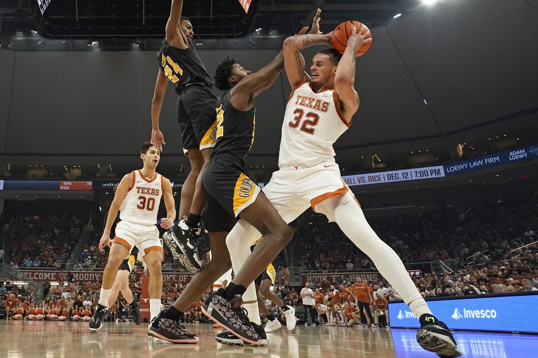 Dec 10, 2022; Austin, Texas, USA; Texas Longhorns forward Christian Bishop (32) drives to the basket against Arkansas Pine-Bluff Golden Lions forward Robert Lewis	(22) and guard AC Curry (24) during the first half at Moody Center. Mandatory Credit: Scott Wachter-USA TODAY Sports