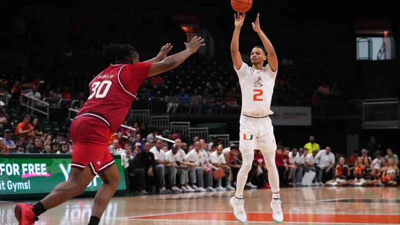 Dec 10, 2022; Coral Gables, Florida, USA; Miami Hurricanes guard Isaiah Wong (2) attempts a three point shot over North Carolina State Wolfpack forward D.J. Burns Jr. (30) during the second half at Watsco Center. Mandatory Credit: Jasen Vinlove-USA TODAY Sports