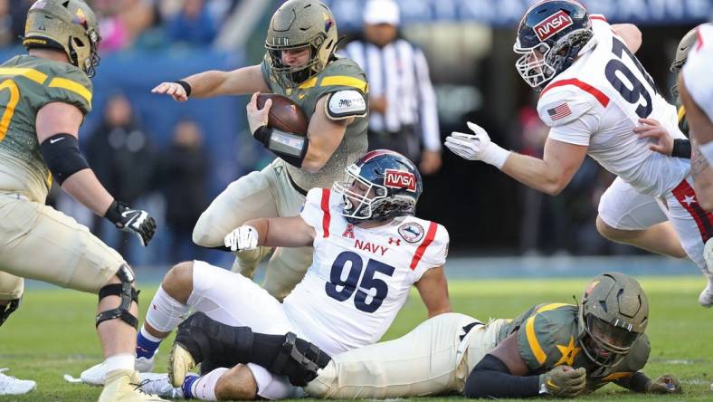 Dec 10, 2022; Philadelphia, Pennsylvania, USA; Army Black Knights quarterback Cade Ballard (18) carries the ball over Navy Midshipmen lineman Jacob Busic (95) during the first half of the 123rd Army-Navy game at Lincoln Financial Field. Mandatory Credit: Danny Wild-USA Today Sports