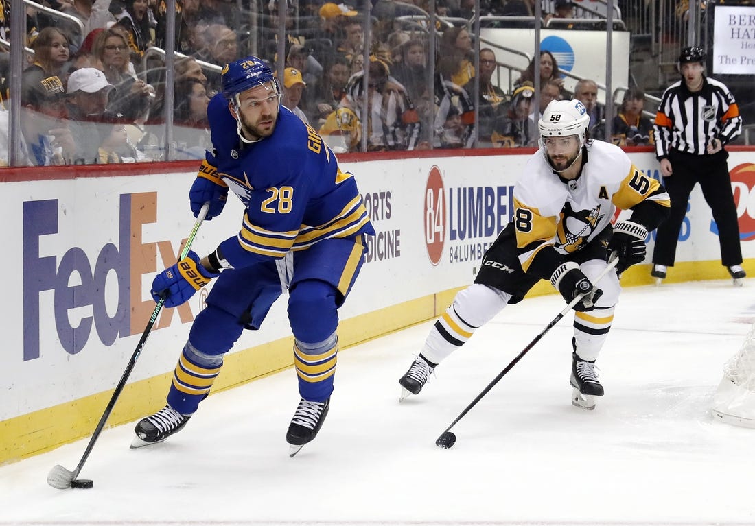 Dec 10, 2022; Pittsburgh, Pennsylvania, USA; Buffalo Sabres left wing Zemgus Girgensons (28) moves the puck against Pittsburgh Penguins defenseman Kris Letang (58) during the second period at PPG Paints Arena. Mandatory Credit: Charles LeClaire-USA TODAY Sports