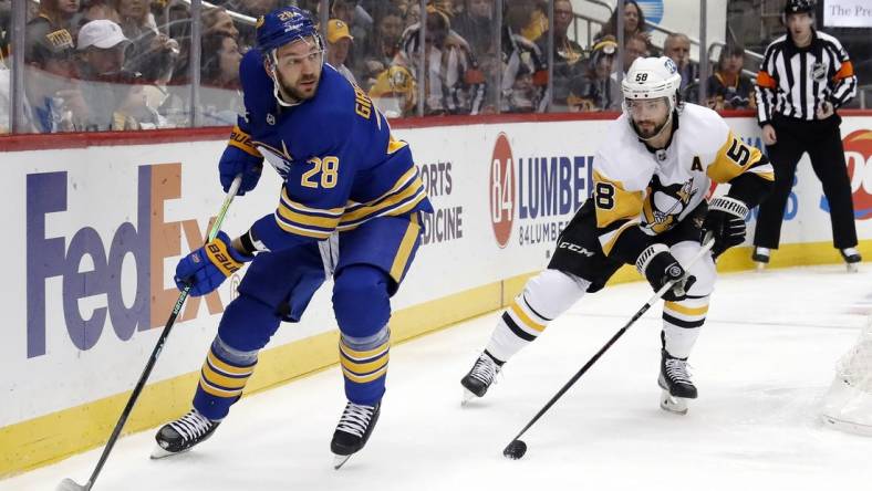 Dec 10, 2022; Pittsburgh, Pennsylvania, USA; Buffalo Sabres left wing Zemgus Girgensons (28) moves the puck against Pittsburgh Penguins defenseman Kris Letang (58) during the second period at PPG Paints Arena. Mandatory Credit: Charles LeClaire-USA TODAY Sports