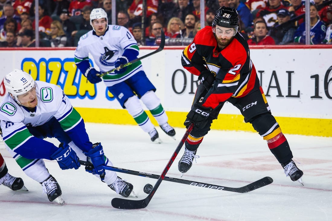 Dec 14, 2022; Calgary, Alberta, CAN; Calgary Flames center Dillon Dube (29) and Vancouver Canucks center Sheldon Dries (15) battle for the puck during the second period at Scotiabank Saddledome. Mandatory Credit: Sergei Belski-USA TODAY Sports