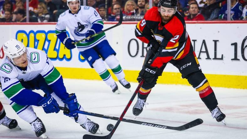 Dec 14, 2022; Calgary, Alberta, CAN; Calgary Flames center Dillon Dube (29) and Vancouver Canucks center Sheldon Dries (15) battle for the puck during the second period at Scotiabank Saddledome. Mandatory Credit: Sergei Belski-USA TODAY Sports